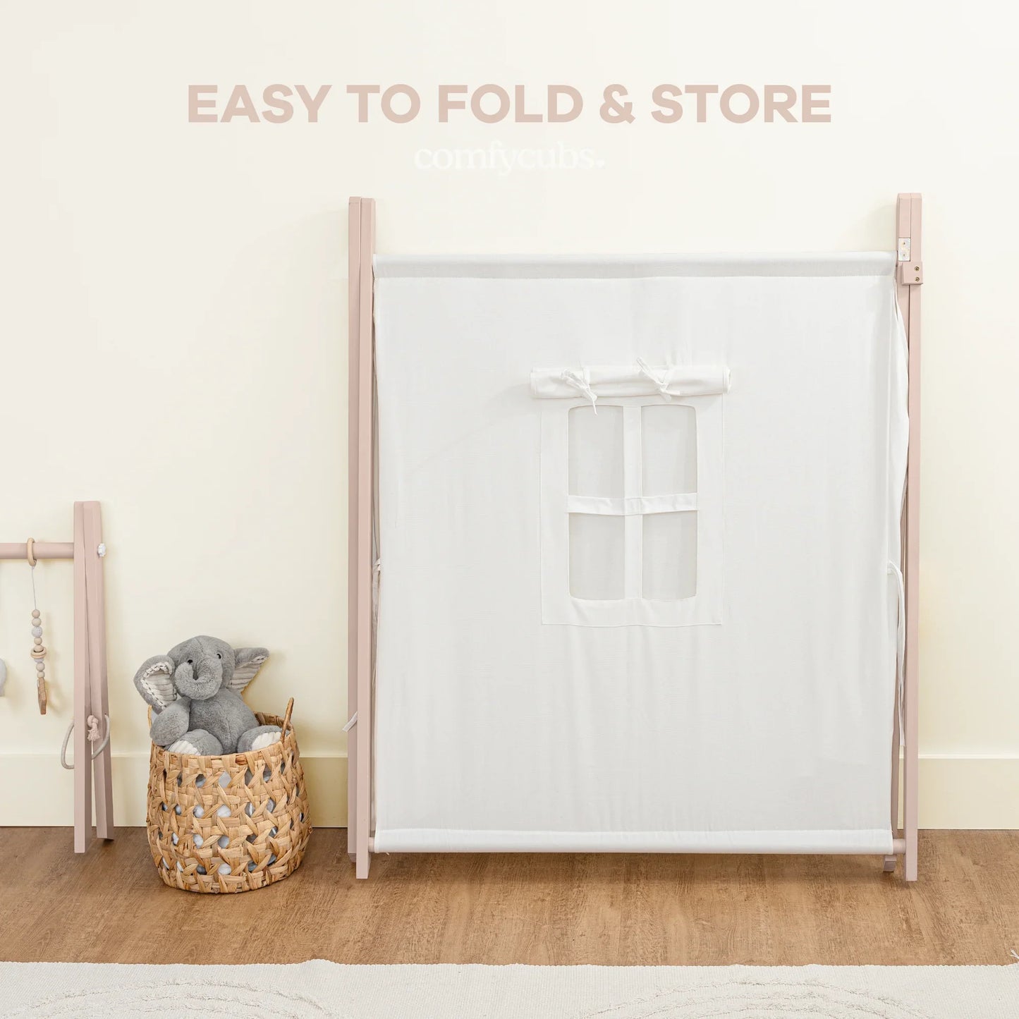 Foldable baby playpen with white mesh, plush elephant in basket, wood floor, Come see us at Awaken, Franklin, Tennessee