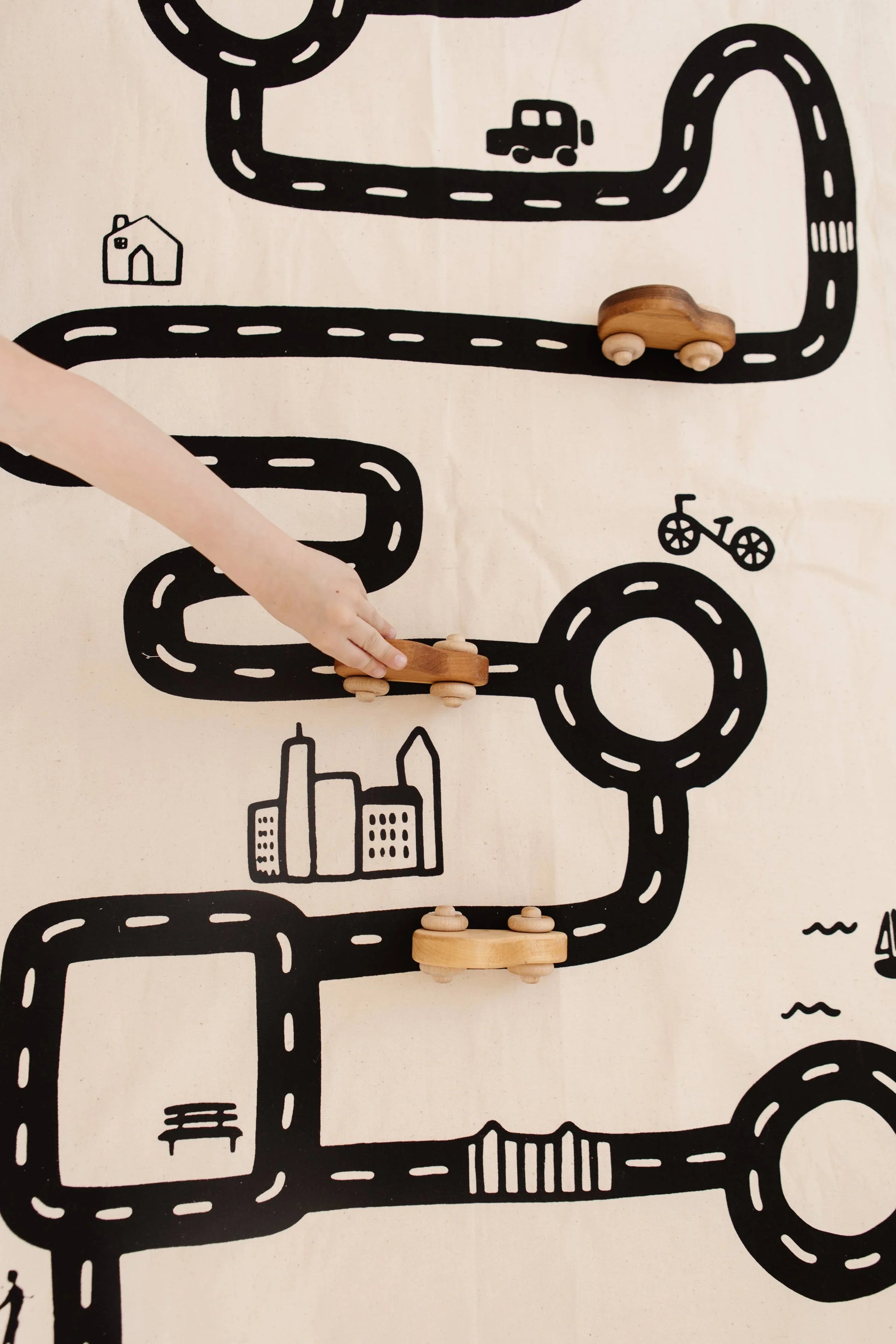 Child's hand moving wooden car on city playmat, road map toys. Come see us at Awaken, Franklin, Tennessee