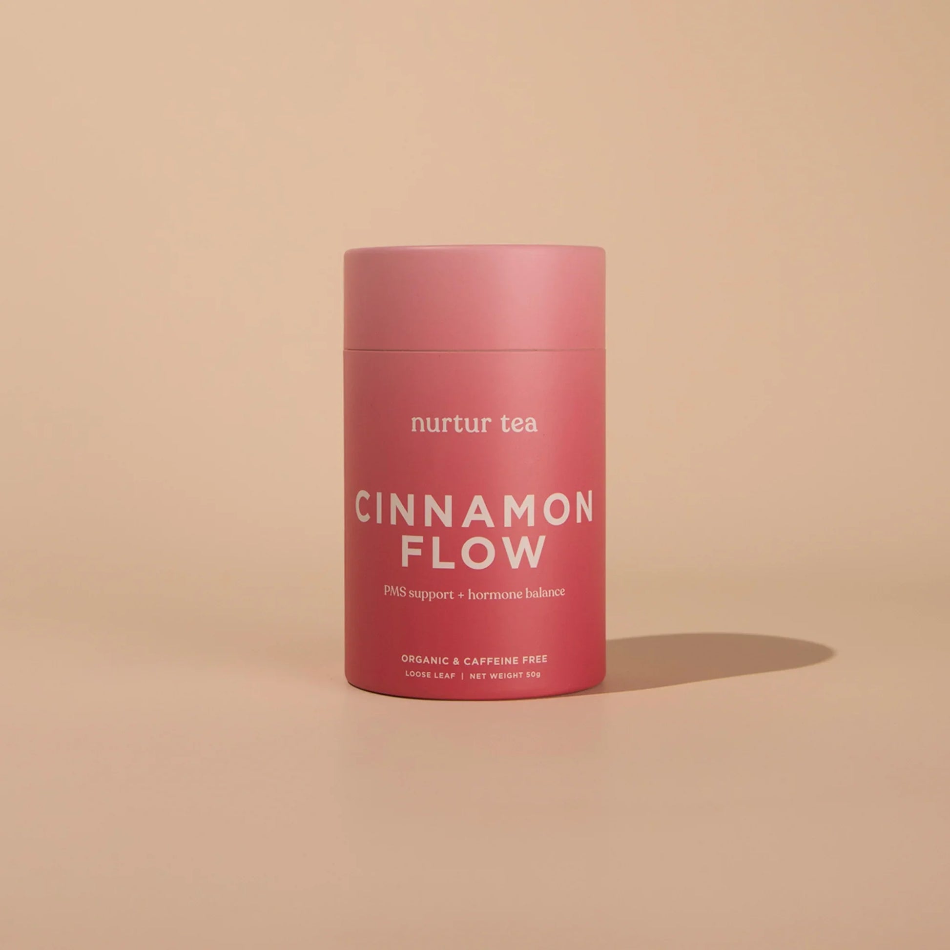 Pink container of Nurtur Tea Cinnamon Flow for PMS support on beige background. Come see us at Awaken, Franklin, Tennessee