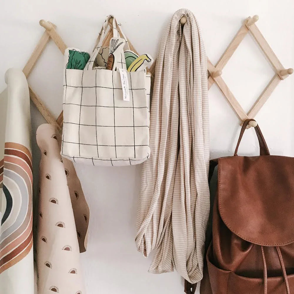 Modern wall hooks with tote bag, play food, scarf and brown backpack. Come see us at Awaken, Franklin, Tennessee.