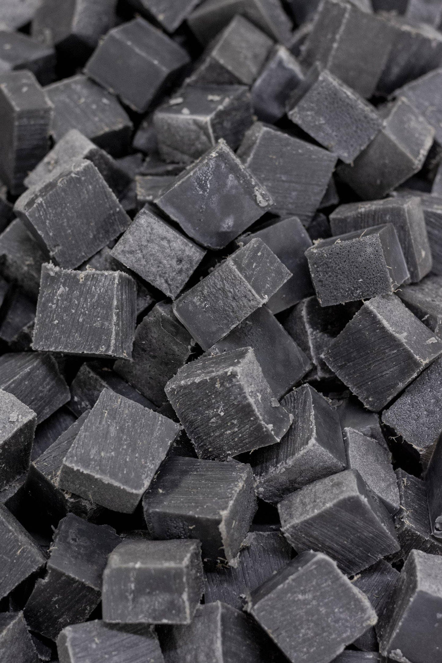 Close-up of black charcoal cubes stacked together, natural texture. Come see us at Awaken, Franklin, Tennessee