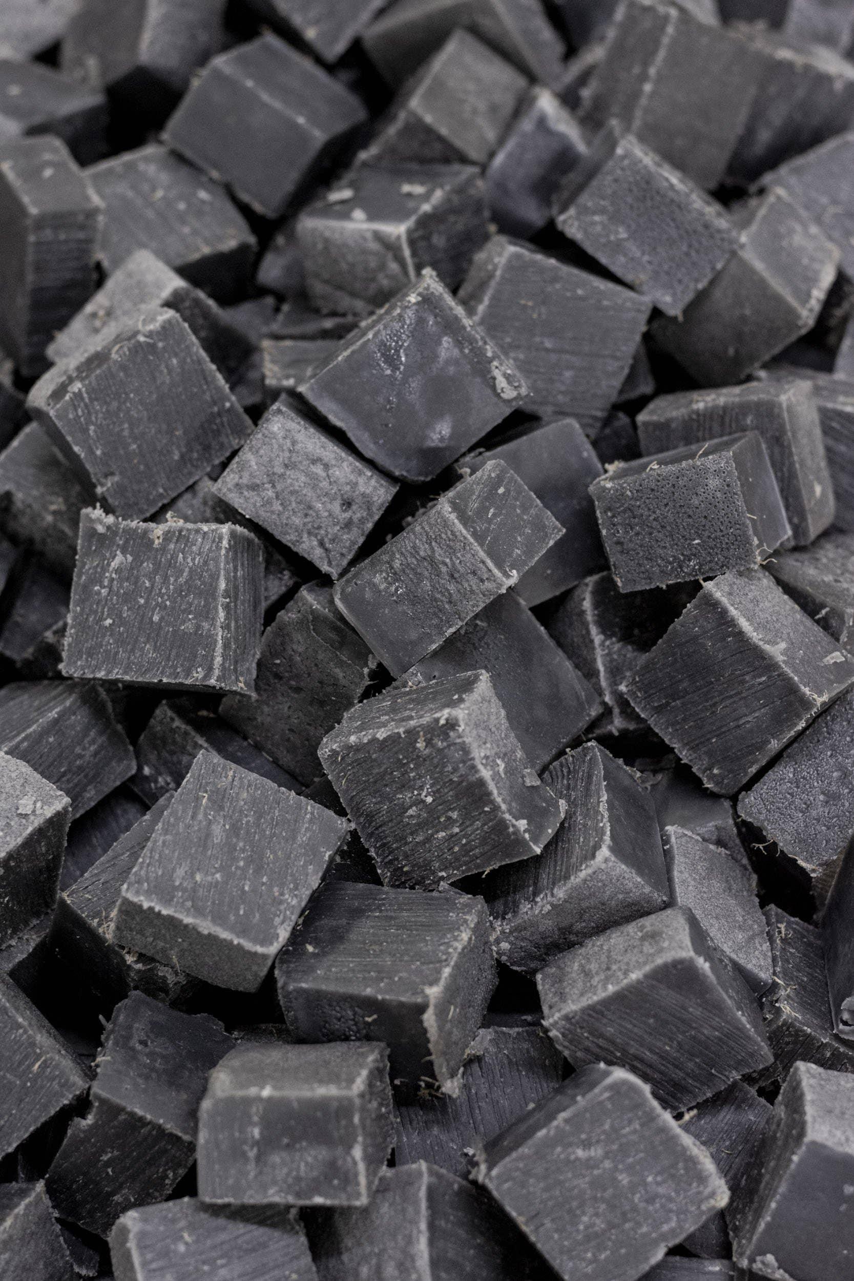 Close-up of black charcoal cubes stacked together, natural texture. Come see us at Awaken, Franklin, Tennessee