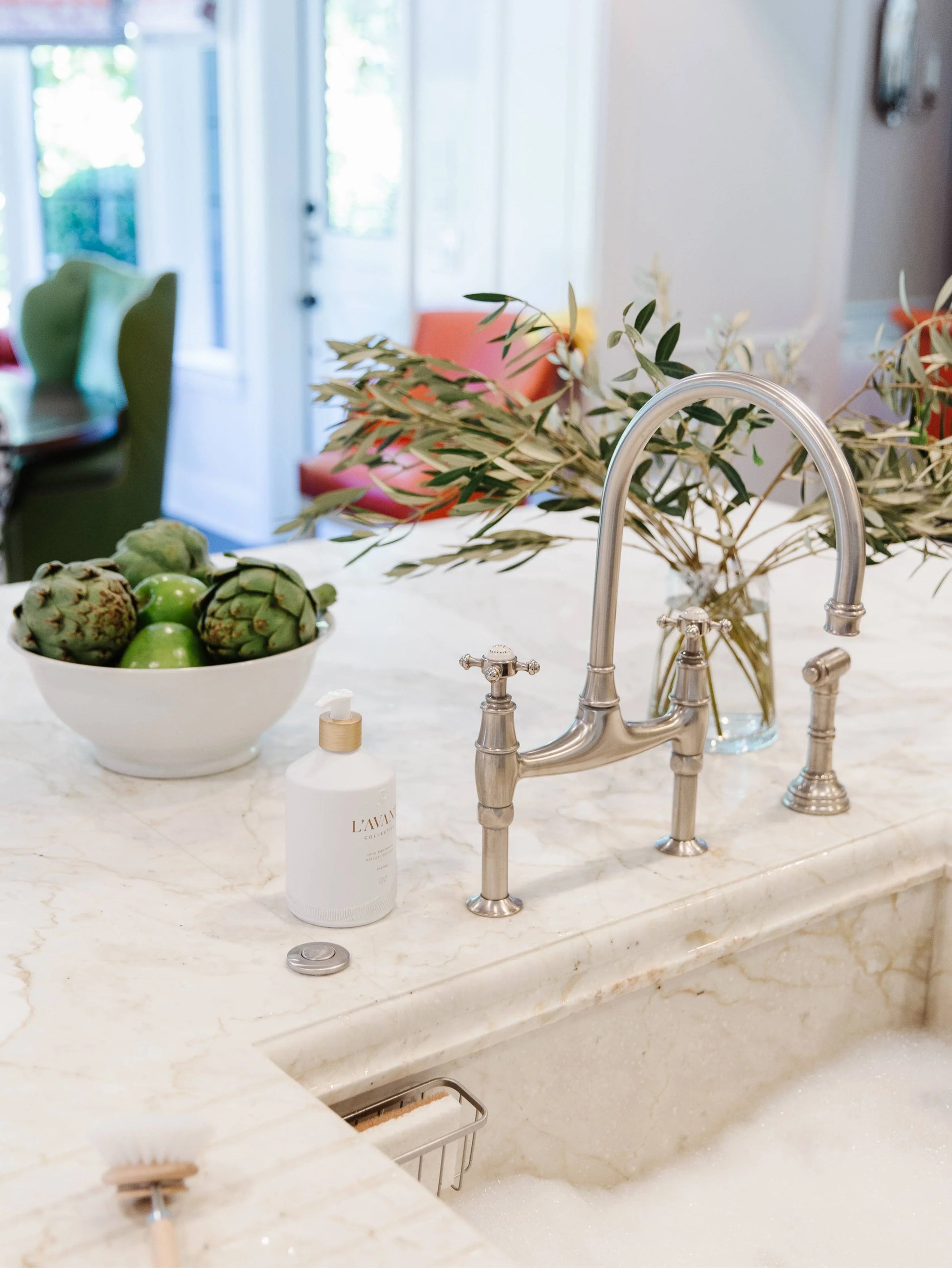 Marble kitchen sink with chrome faucet, dish soap, bowl of artichokes, greenery, and Come see us at Awaken, Franklin, Tennessee