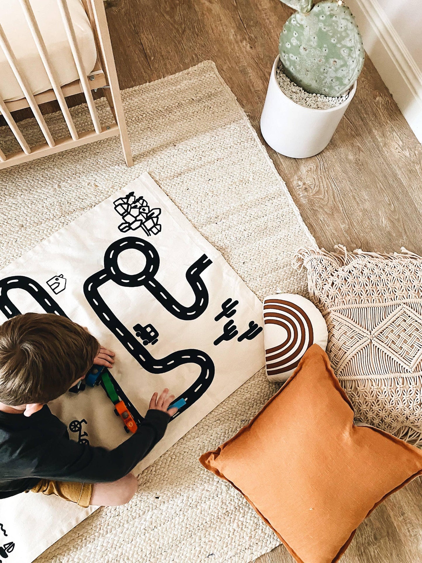 Child playing with toy train on a play mat in cozy nursery, neutral decor, Come see us at Awaken, Franklin, Tennessee
