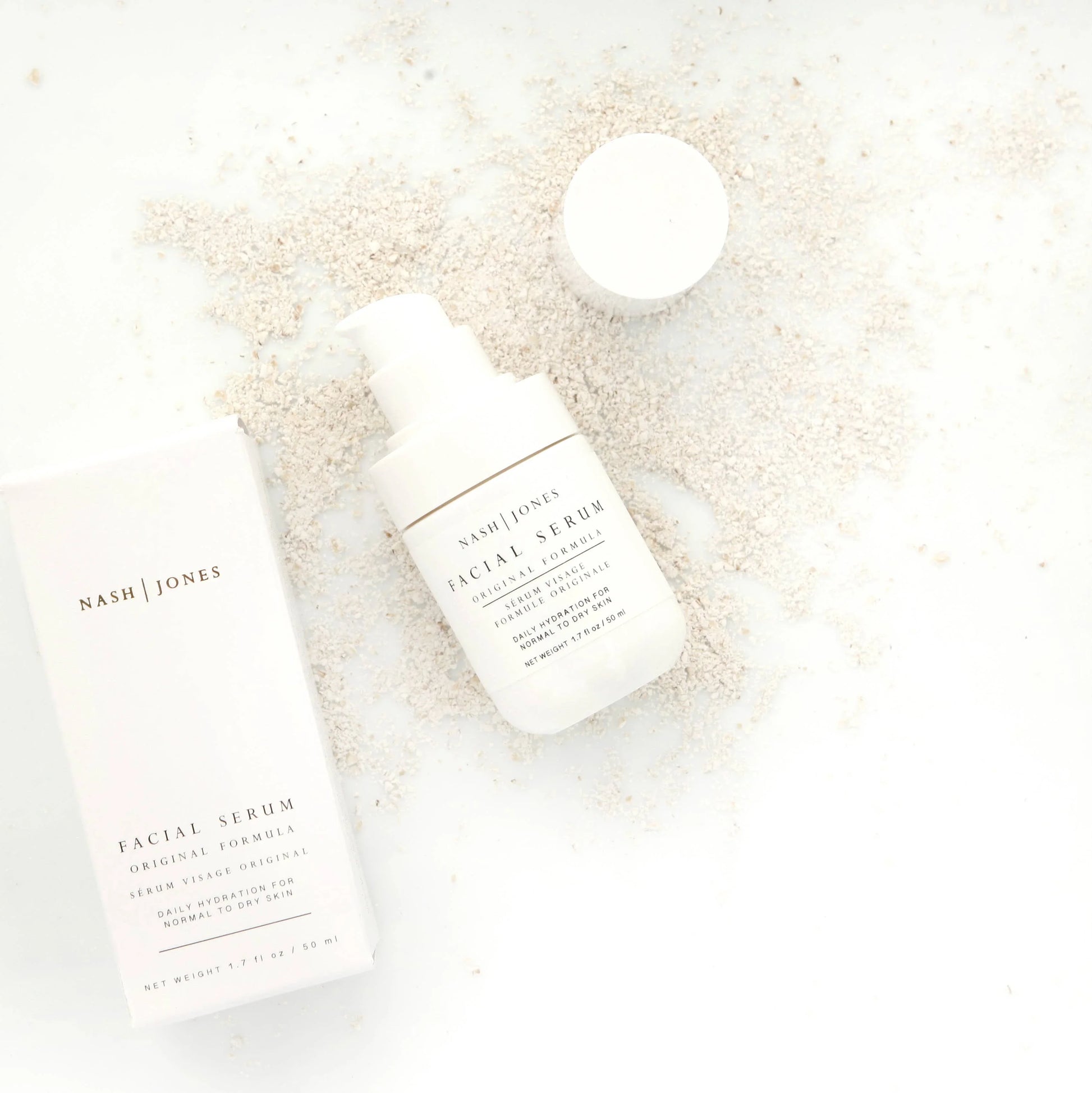 Nash Jones facial serum with box on white surface and beige powder background. Come see us at Awaken, Franklin, Tennessee