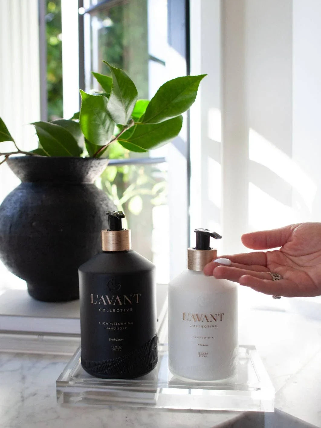 L'AVANT hand soap and lotion on tray by window, plant in background. Come see us at Awaken, Franklin, Tennessee.