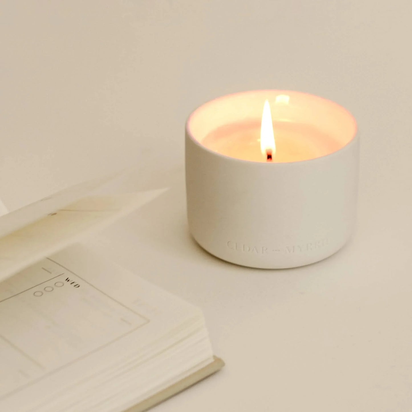 Minimalist white candle burning beside an open planner, Come see us at Awaken, Franklin, Tennessee
