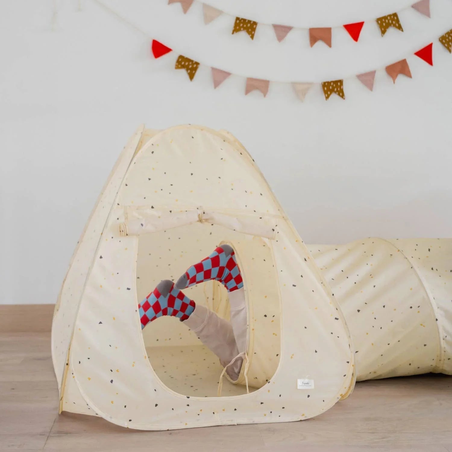 Child's feet in red and blue checkered socks inside a cream play tent with tunnel and bunting flags. Come see us at Awaken, Franklin, Tennessee