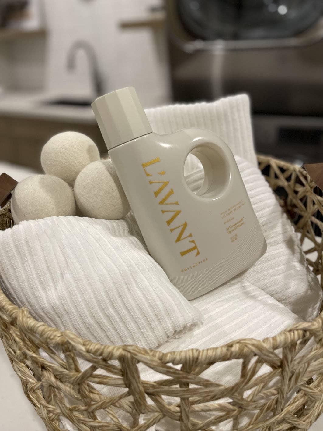 L'AVANT laundry detergent bottle, wool dryer balls, and white towels in a basket. Come see us at Awaken, Franklin, Tennessee