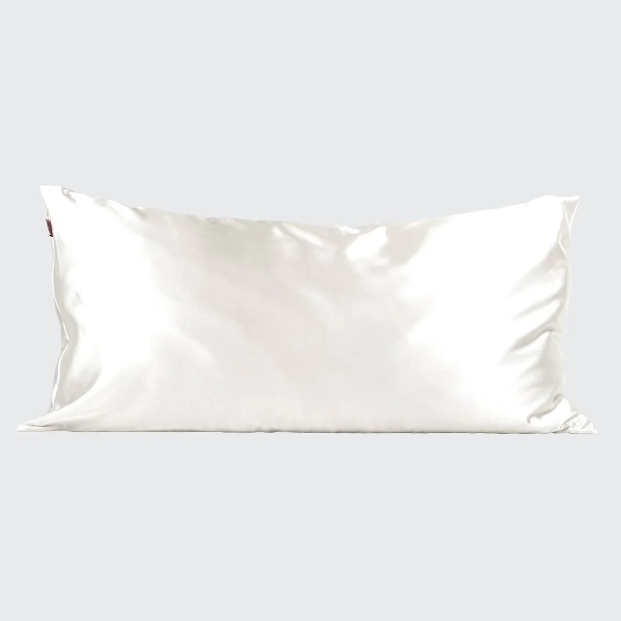 White satin rectangular pillow with smooth, shiny fabric on gray background. Come see us at Awaken, Franklin, Tennessee