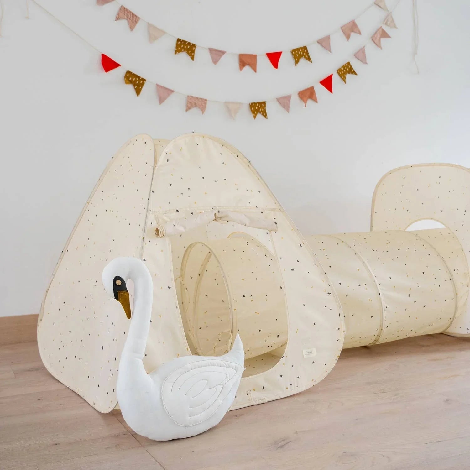 Children's play tent and tunnel set with speckled pattern and soft swan toy on wooden floor, colorful bunting above, Come see us at Awaken, Franklin, Tennessee