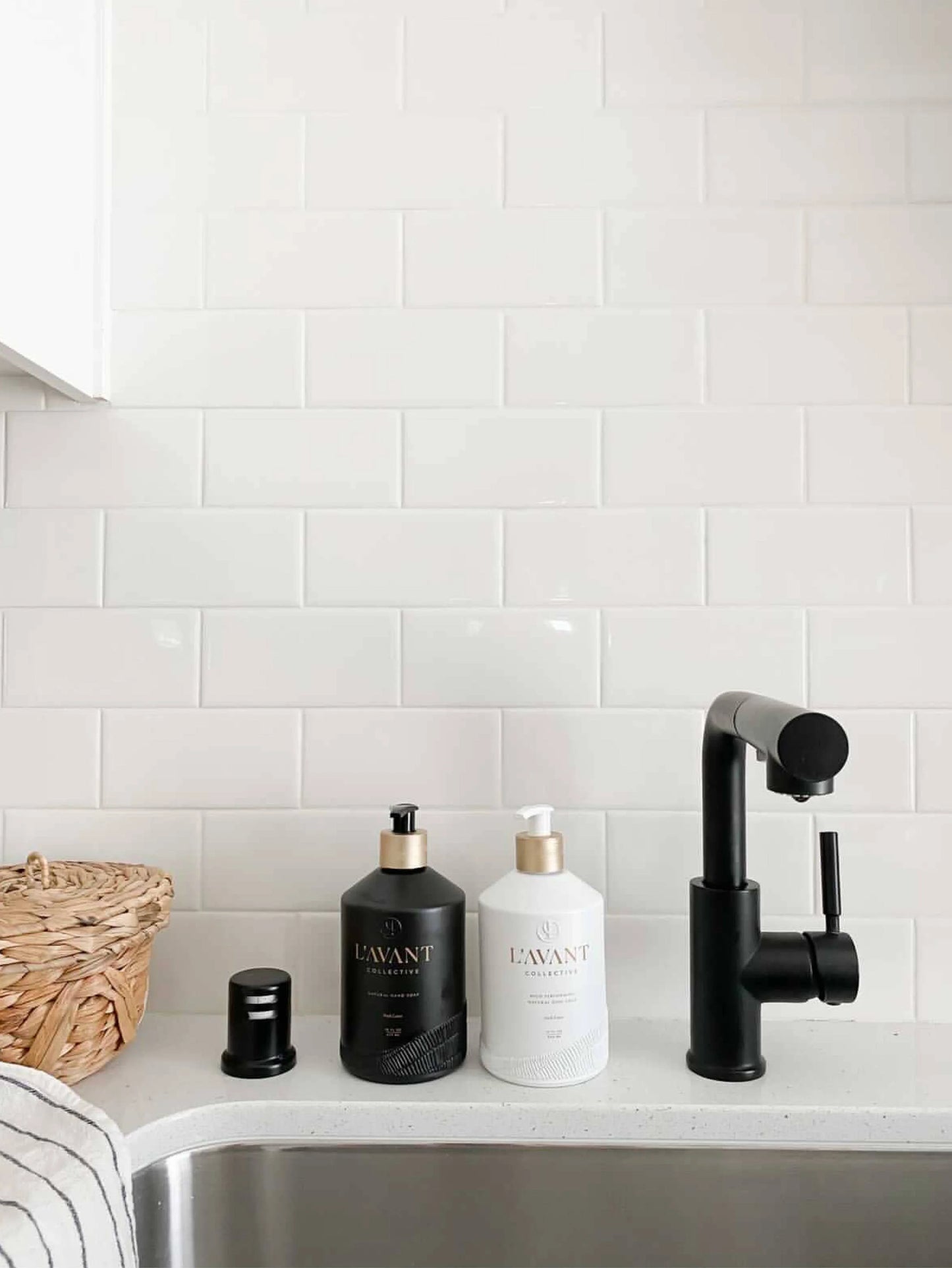 L'AVANT Collective soap bottles beside black kitchen faucet on white tile backsplash, Come see us at Awaken, Franklin, Tennessee