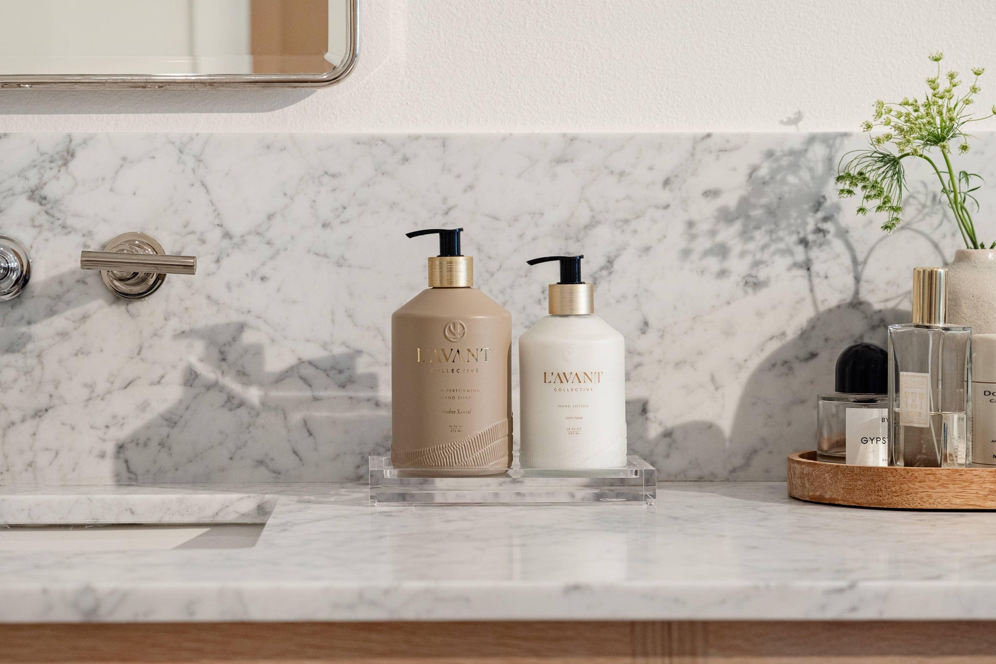 L'Avant Collective hand soap and lotion on marble bathroom counter, greenery and perfumes nearby. Come see us at Awaken, Franklin, Tennessee