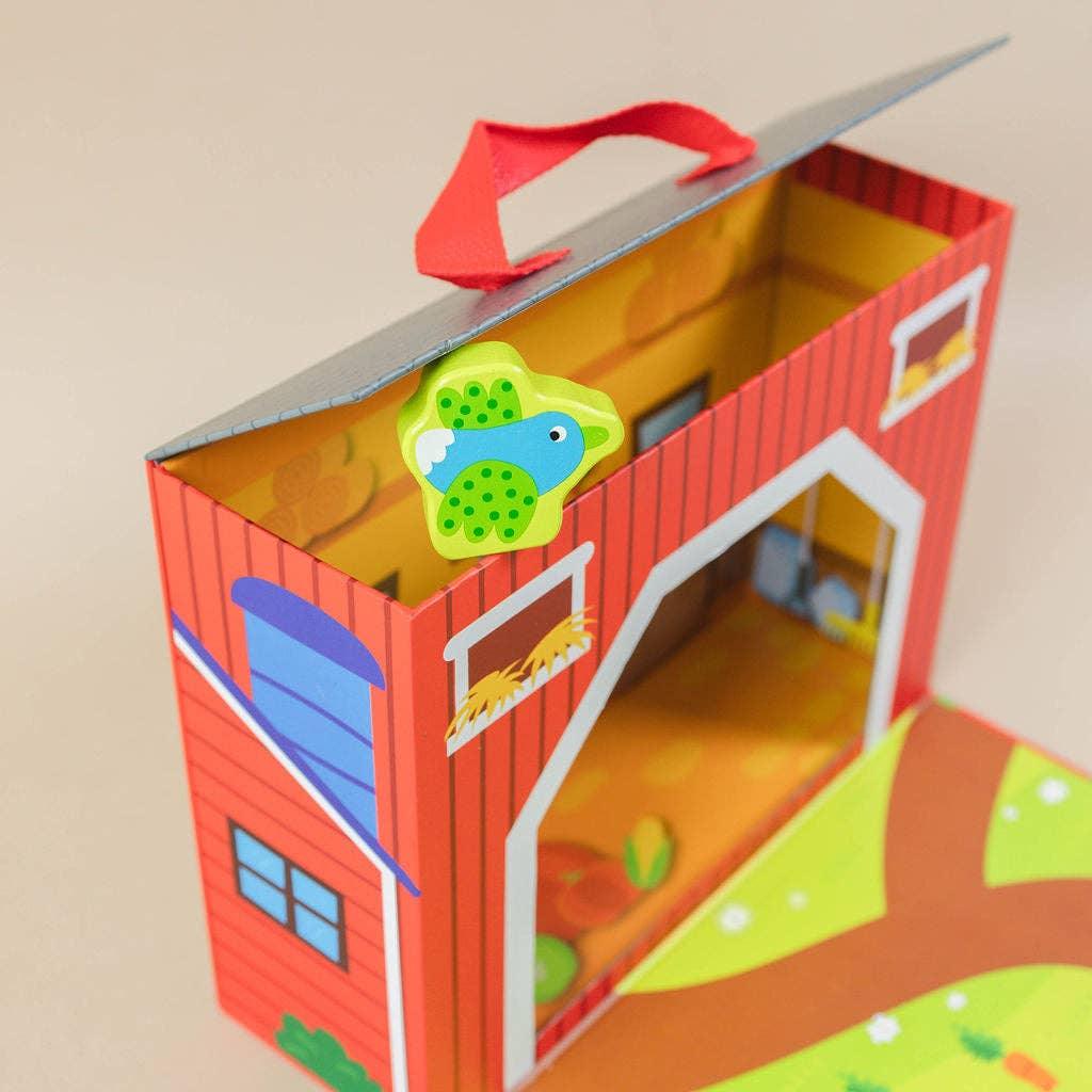 Red barn-shaped toy with blue bird magnet and farm-themed playset inside. Come see us at Awaken, Franklin, Tennessee