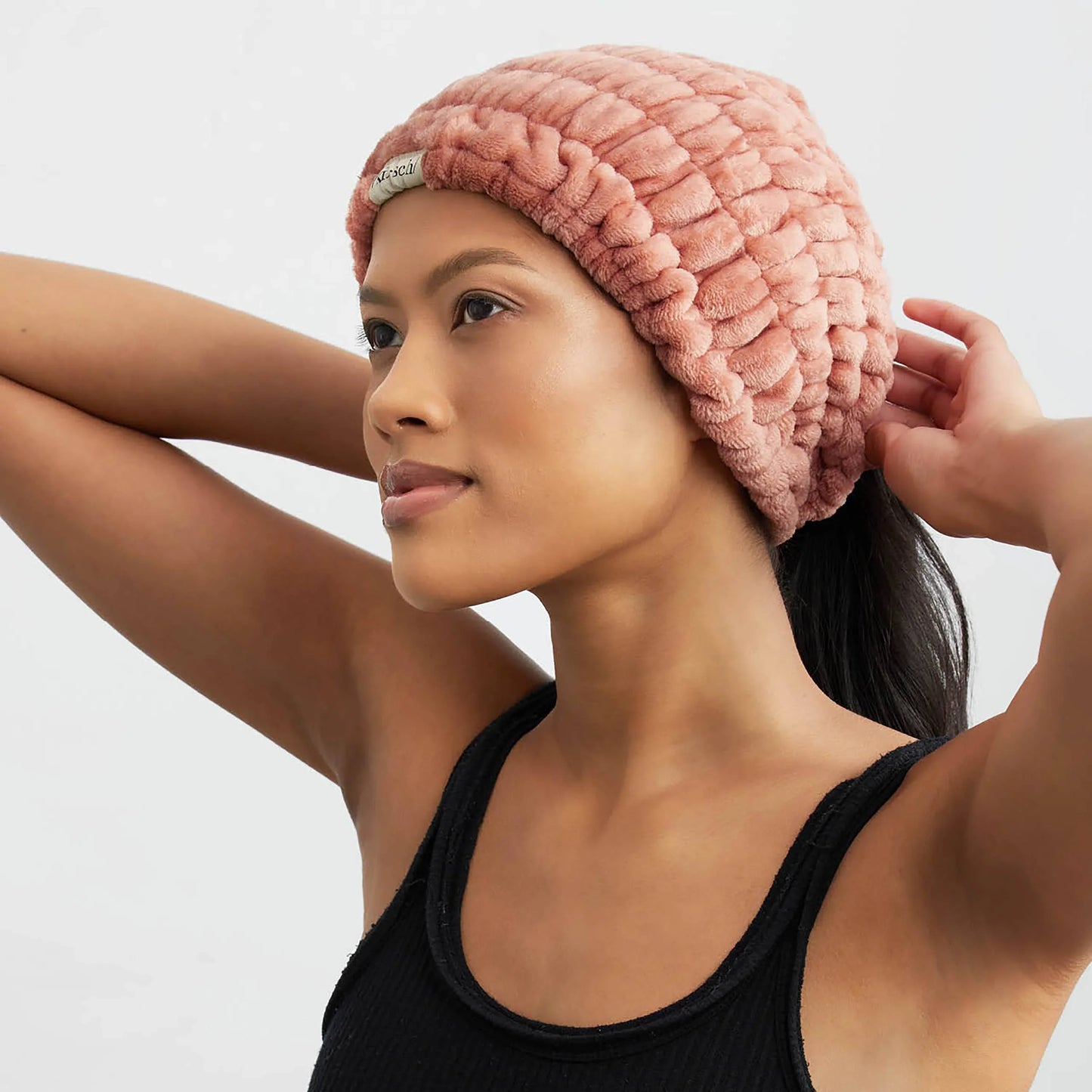 Woman wearing a soft pink textured beanie and black tank top, posing with hands behind head. Come see us at Awaken, Franklin, Tennessee