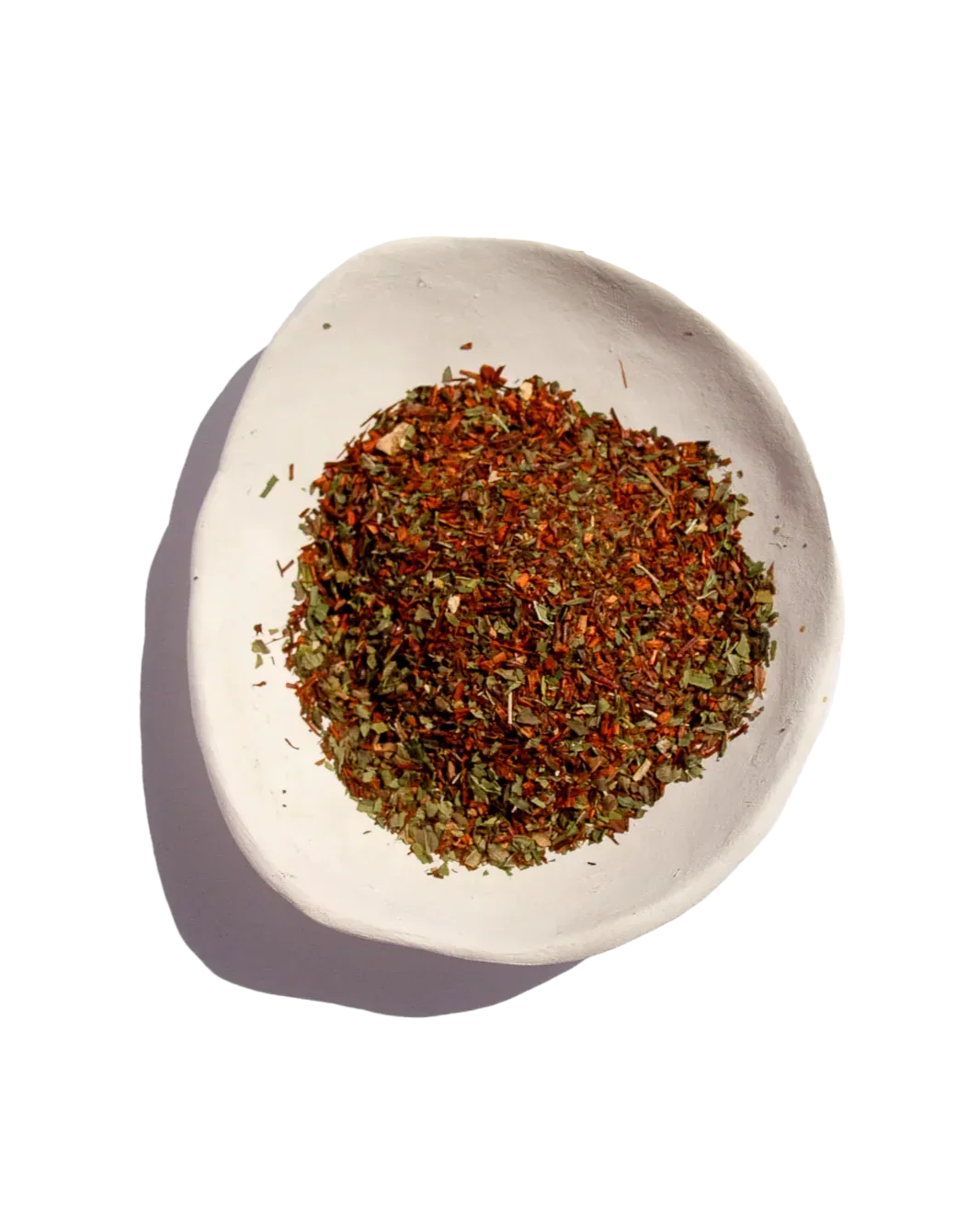White bowl with loose herbal tea blend of red and green leaves, bright background, Come see us at Awaken, Franklin, Tennessee