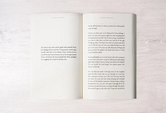 Open book with inspiring text on a light wooden surface, promoting self-care and healing. Come see us at Awaken, Franklin, Tennessee