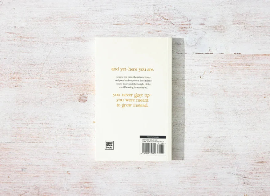 Back cover of a white book with inspirational gold text on a white wooden surface. Come see us at Awaken, Franklin, Tennessee