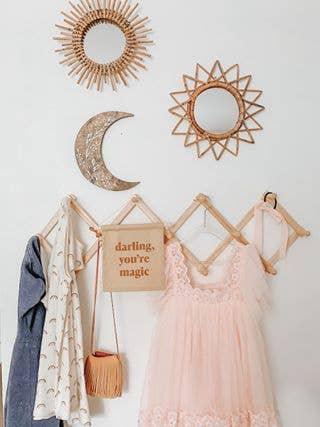 Boho chic nursery wall decor with sun mirrors, moon art, pink dress, and quote sign. Come see us at Awaken, Franklin, Tennessee.