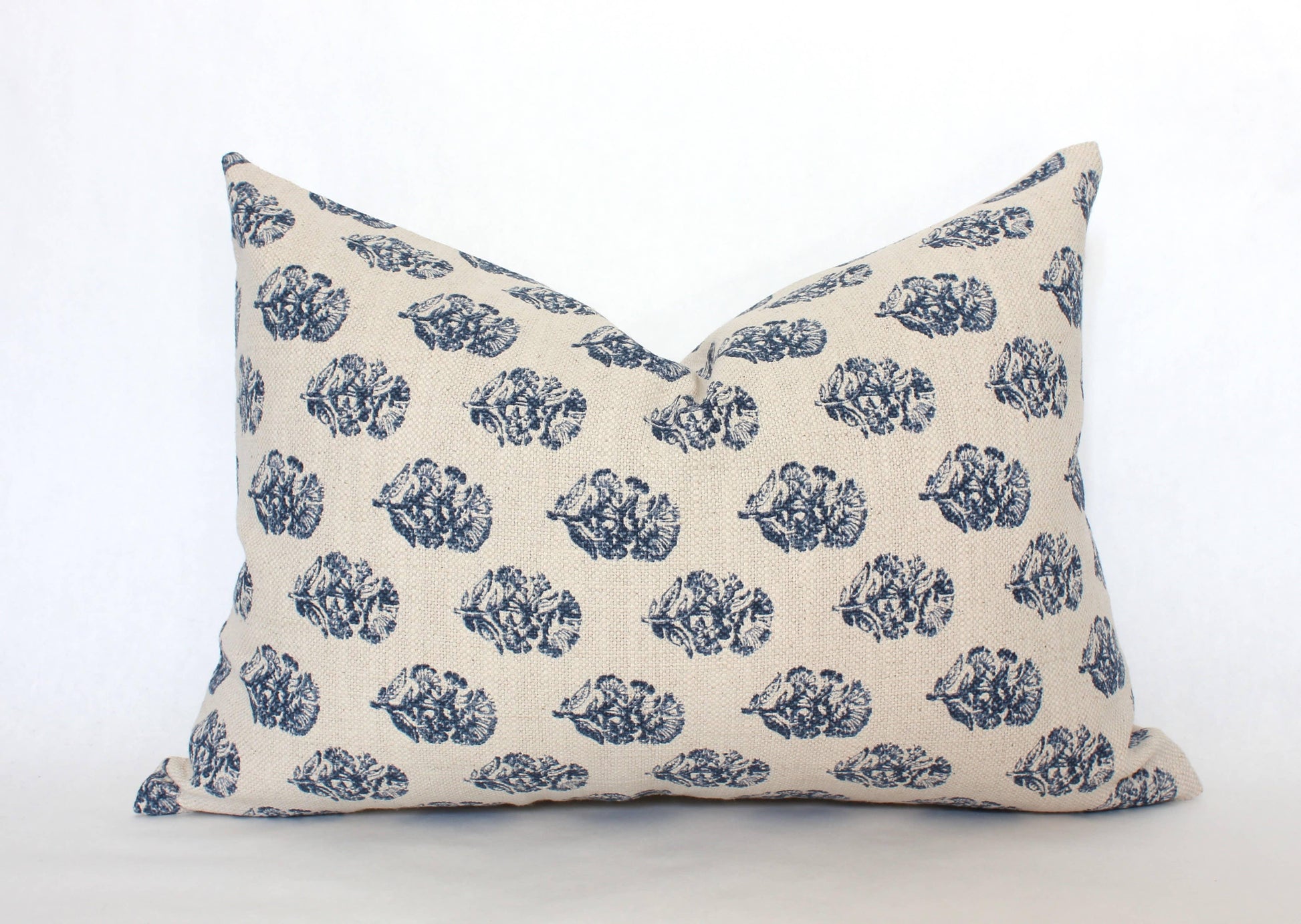 Decorative beige pillow with blue leaf pattern on white background. Come see us at Awaken, Franklin, Tennessee