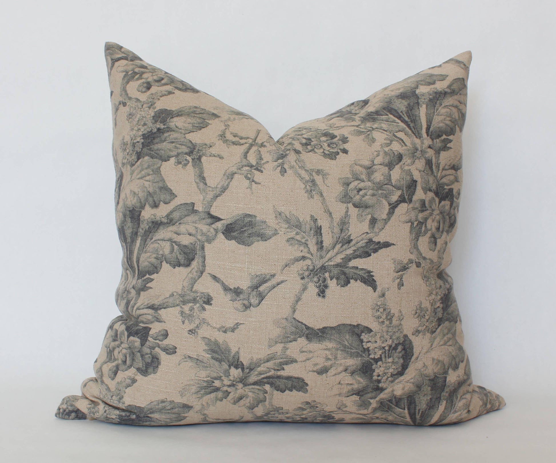 Decorative beige pillow with black floral and bird print on white background. Come see us at Awaken, Franklin, Tennessee