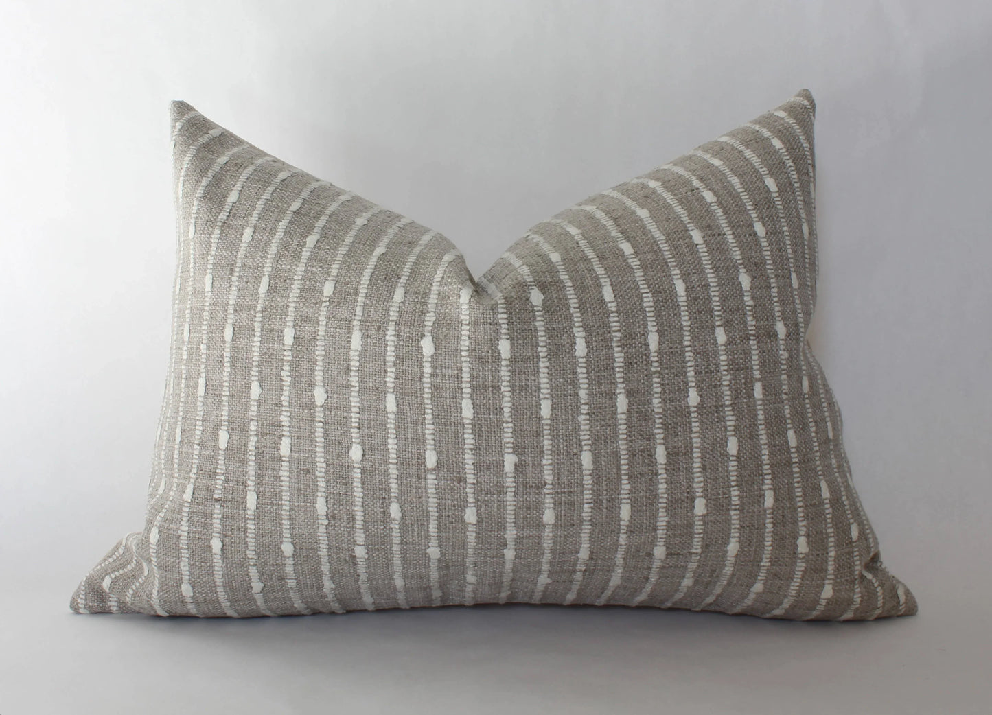 Beige lumbar pillow with white dotted vertical stripes on light background, Come see us at Awaken, Franklin, Tennessee
