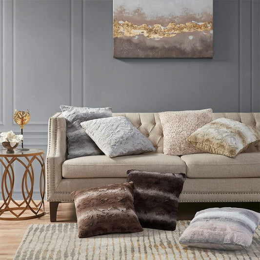 Beige tufted sofa with assorted plush decorative pillows and gold accent side table in modern living room. Come see us at Awaken, Franklin, Tennessee