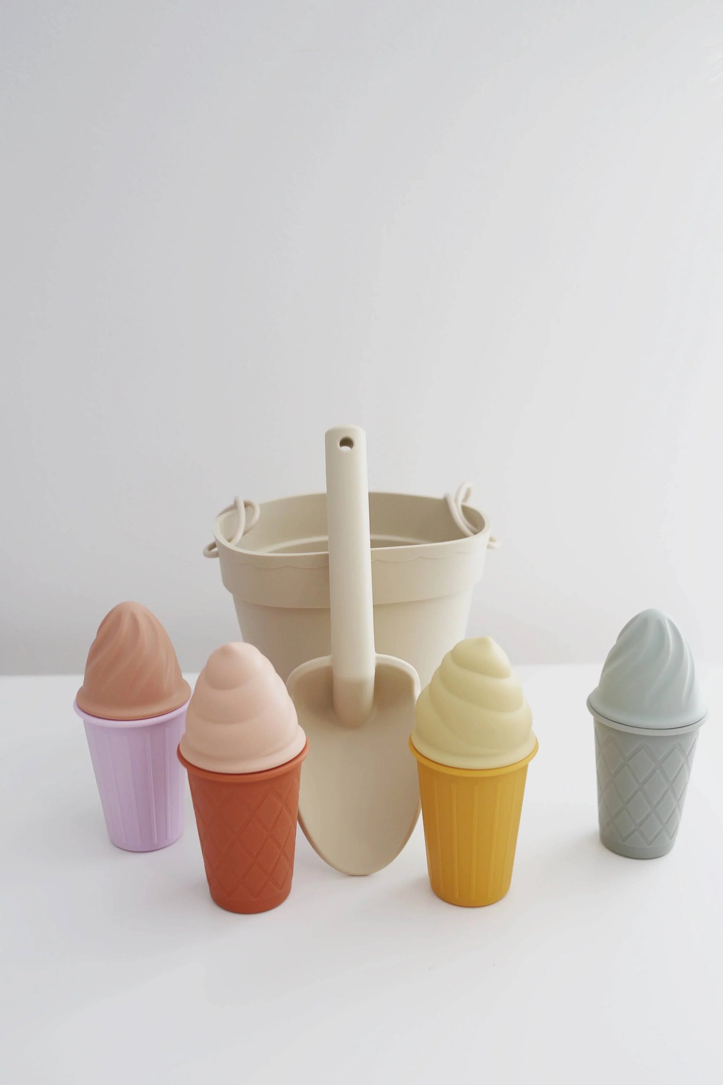 Silicone ice cream cone toys with beige bucket and shovel on white surface. Come see us at Awaken, Franklin, Tennessee
