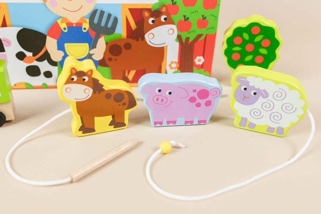 Wooden farm animal lacing toy with horse, pig, sheep on beige background, Come see us at Awaken, Franklin, Tennessee