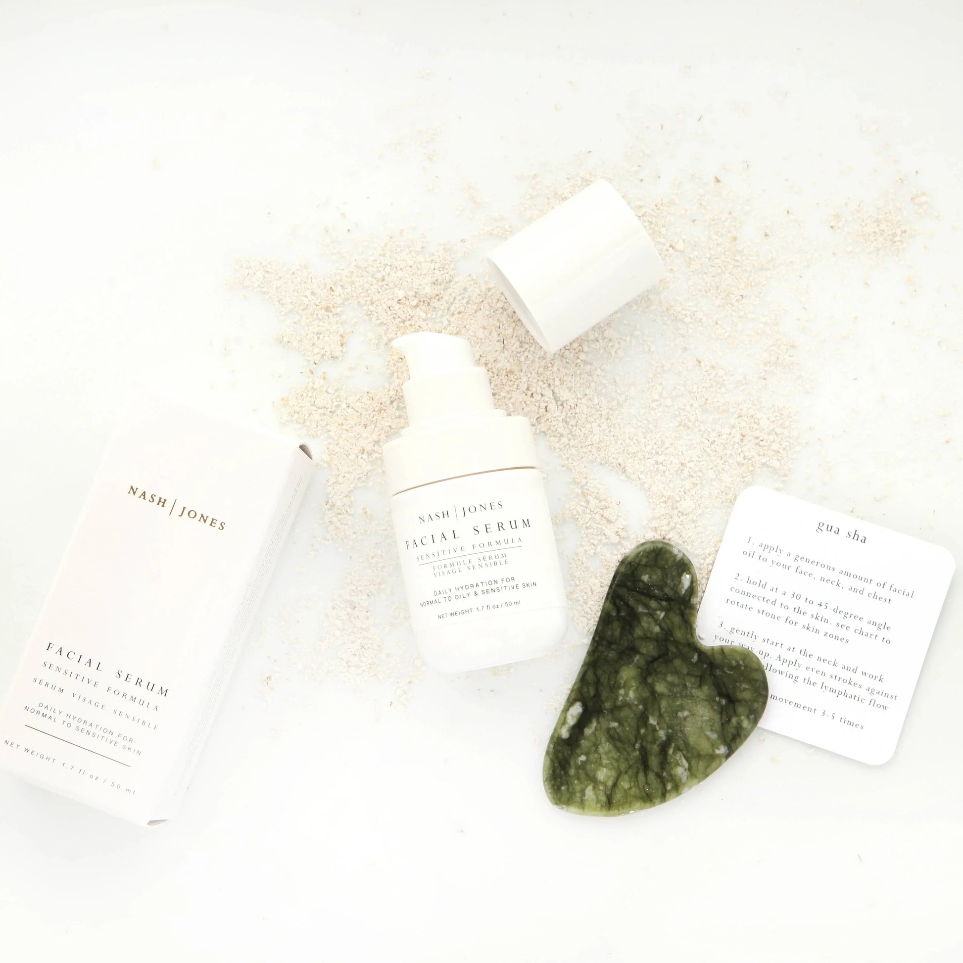 Nash Jones facial serum, gua sha tool, and instructions on white background with scattered powder. Come see us at Awaken, Franklin, Tennessee