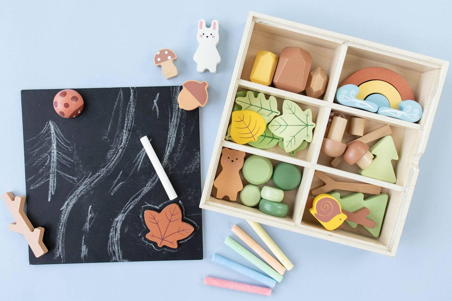 Wooden nature-themed toys with chalk drawing on blackboard, pastel chalks scattered. Come see us at Awaken, Franklin, Tennessee