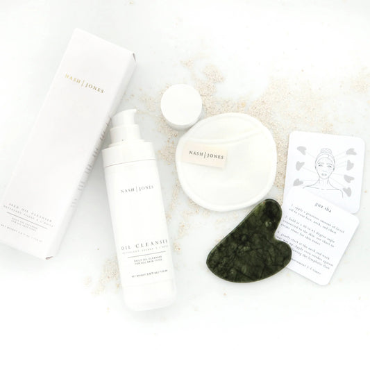 Nash Jones oil cleanser with packaging, cleansing pad, gua sha tool, and instructions. Come see us at Awaken, Franklin, Tennessee