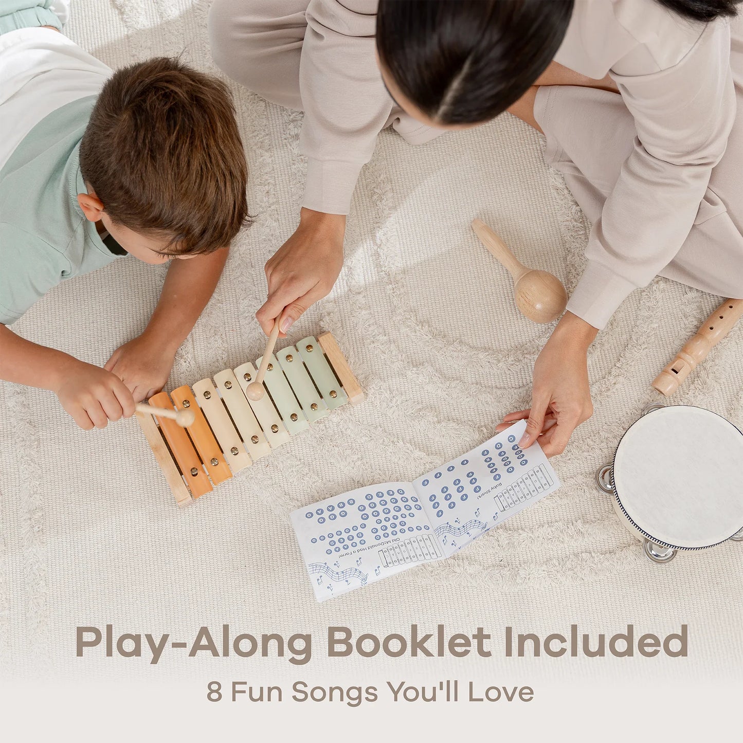 Child and adult playing xylophone with music booklet, maraca, tambourine, and flute on rug. Come see us at Awaken, Franklin, Tennessee