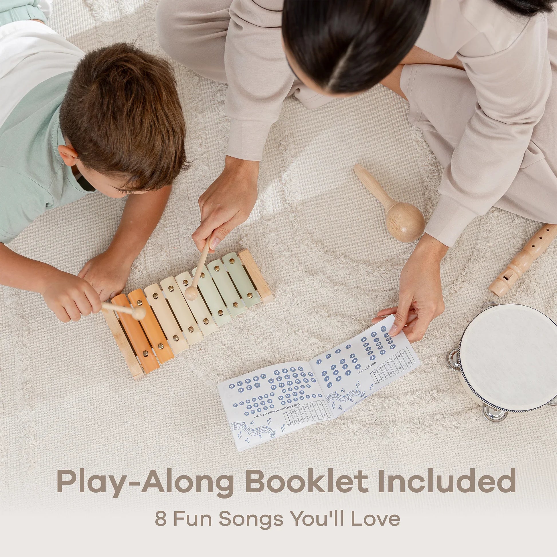Child and adult playing xylophone with music booklet, maraca, tambourine, and flute on rug. Come see us at Awaken, Franklin, Tennessee