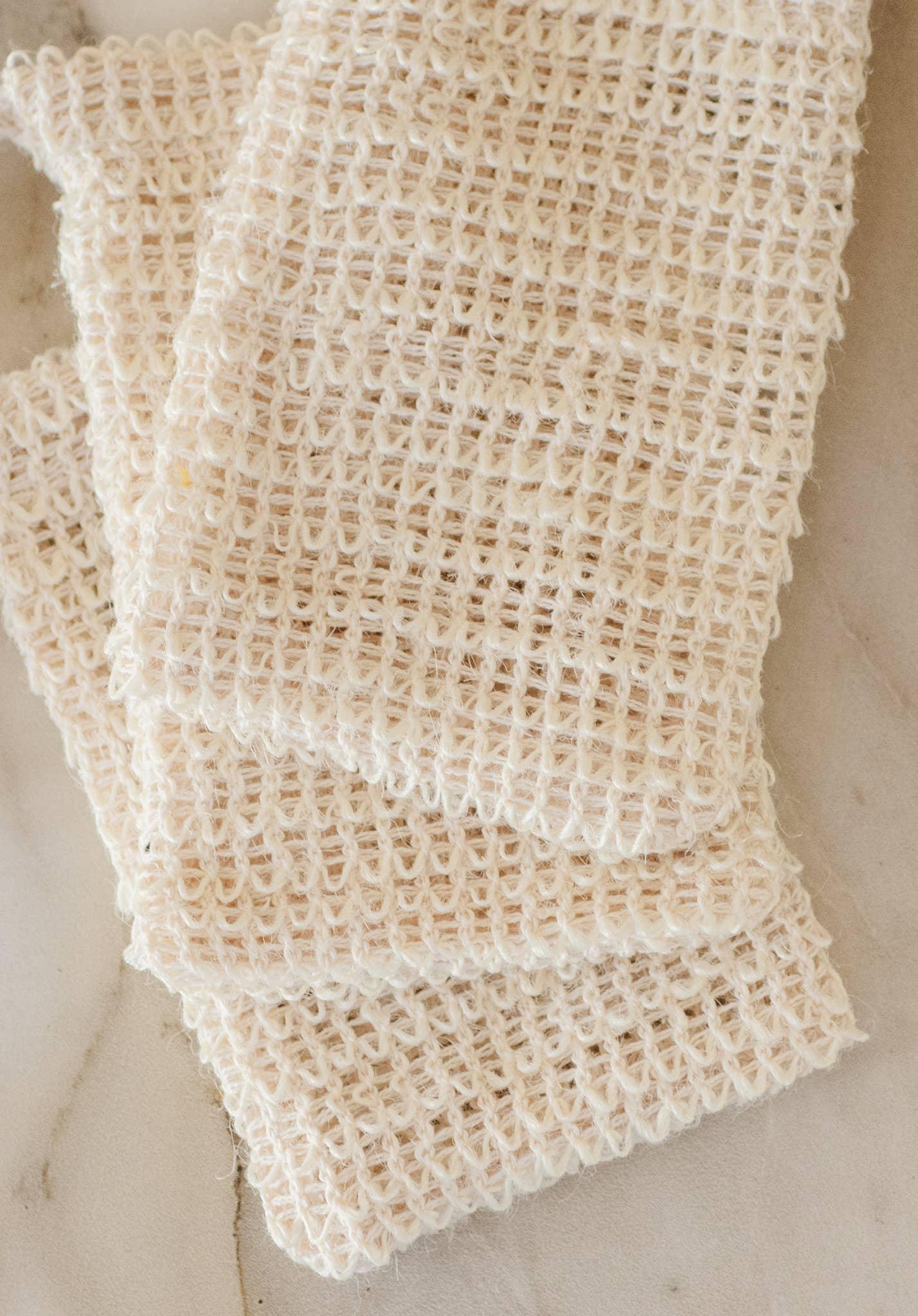 Stack of beige knitted fabric squares on a marble surface. Come see us at Awaken, Franklin, Tennessee
