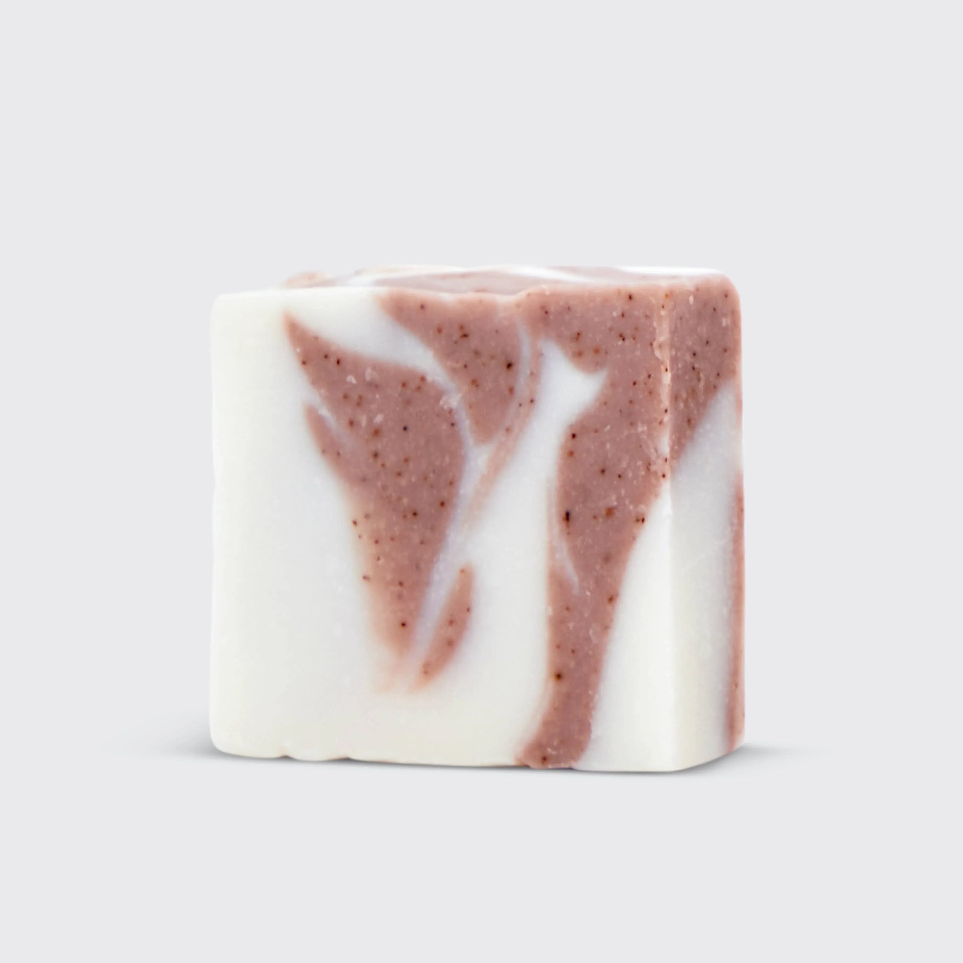 White and brown swirled artisan soap bar with speckled texture on light gray background. Come see us at Awaken, Franklin, Tennessee