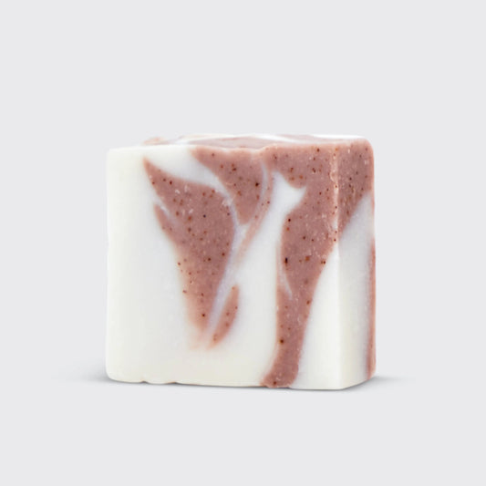 White and brown swirled artisan soap bar with speckled texture on light gray background. Come see us at Awaken, Franklin, Tennessee
