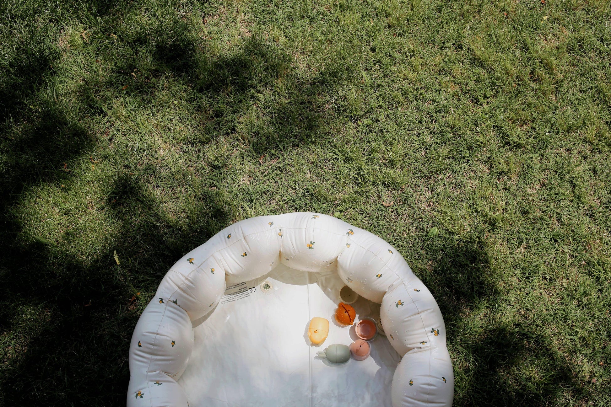 Inflatable white baby pool with small colorful toys inside on green grass in sunlight and shadow. Come see us at Awaken, Franklin, Tennessee
