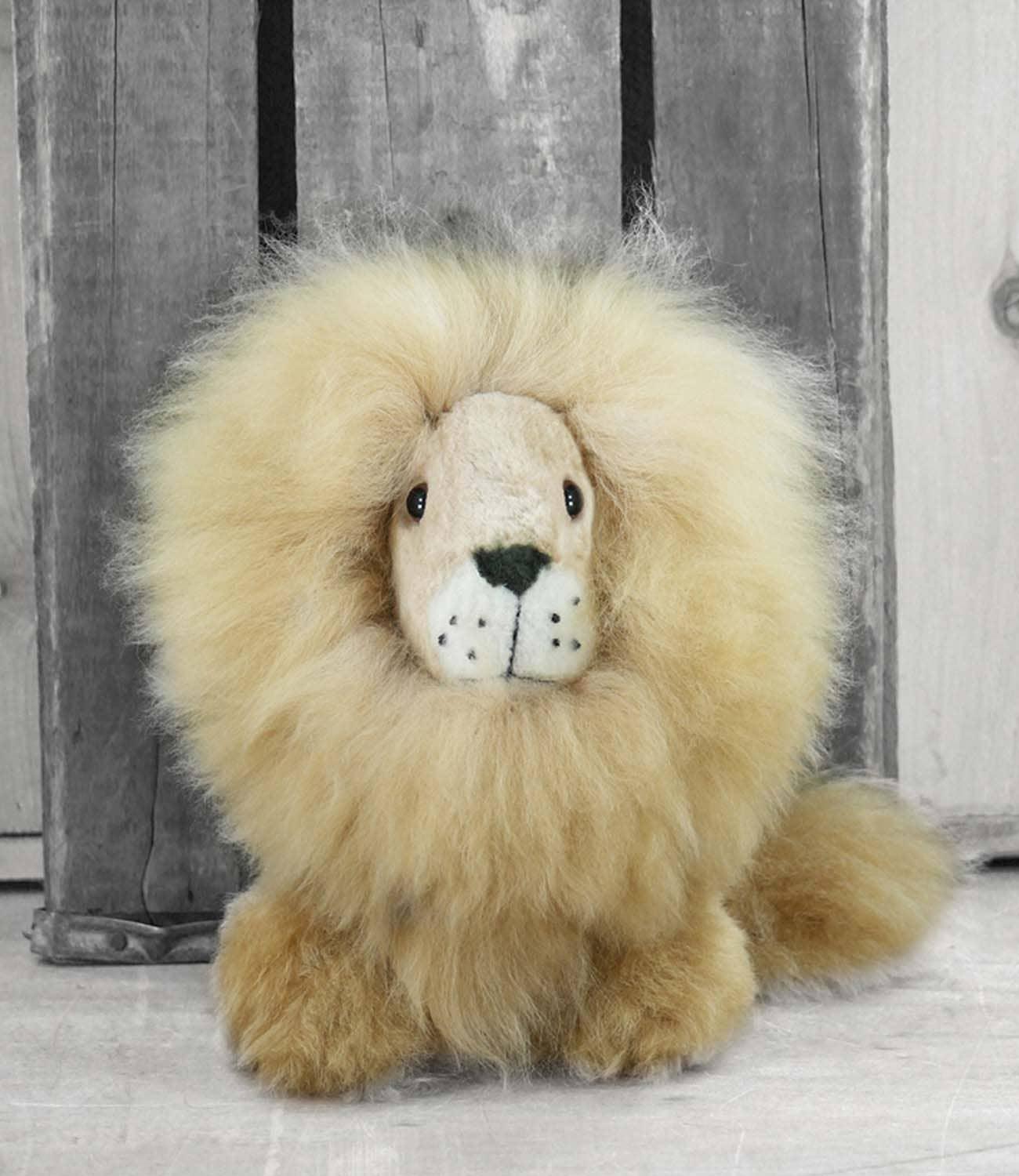 Fluffy plush lion toy with large mane on wooden background, Come see us at Awaken, Franklin, Tennessee