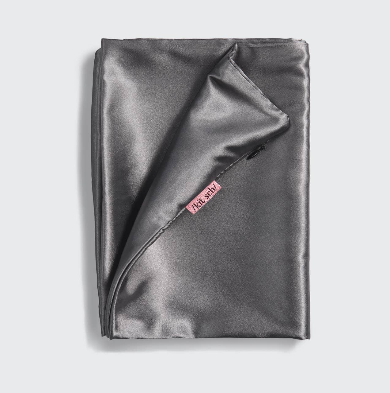 Folded gray satin pillowcase with zipper and pink kit.schl tag on white background. Come see us at Awaken, Franklin, Tennessee