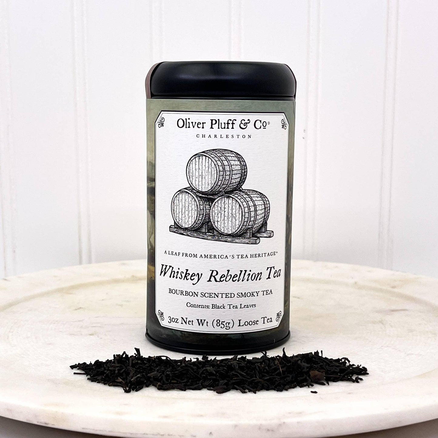 Oliver Pluff & Co Whiskey Rebellion loose black tea with bourbon scent on white surface, barrels illustration. Come see us at Awaken, Franklin, Tennessee