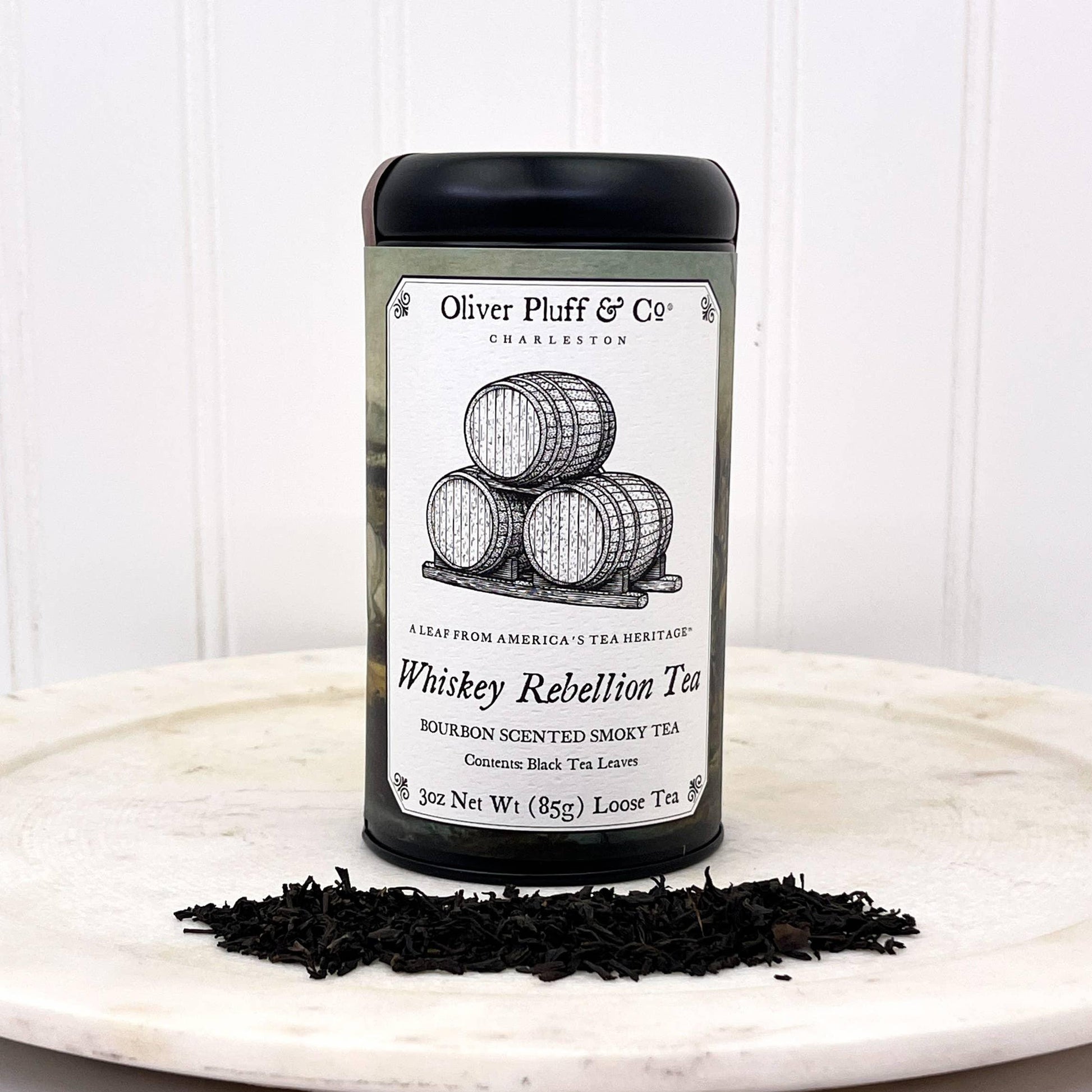 Oliver Pluff & Co Whiskey Rebellion loose black tea with bourbon scent on white surface, barrels illustration. Come see us at Awaken, Franklin, Tennessee