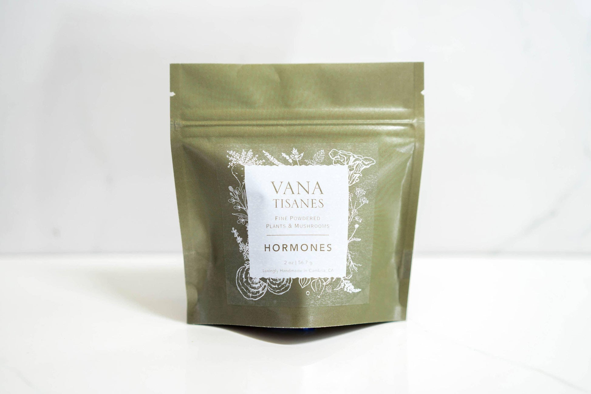 Green package of Vana Tisanes fine powdered plants and mushrooms labeled Hormones on white surface. Come see us at Awaken, Franklin, Tennessee