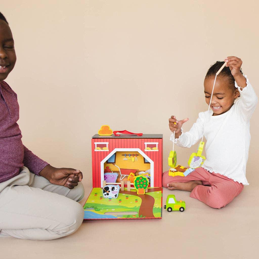 Two children playing with a wooden barn and farm animal toy set indoors. Come see us at Awaken, Franklin, Tennessee