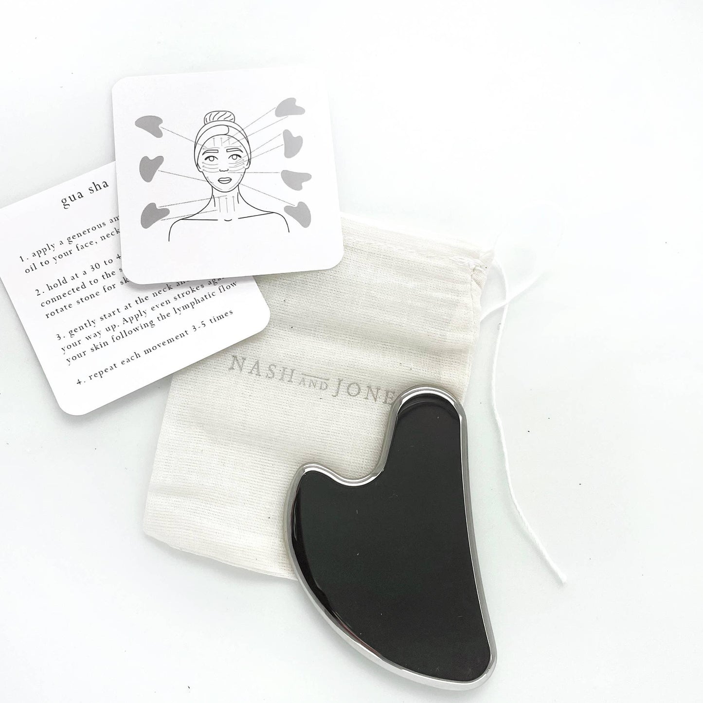 Black gua sha tool with instruction cards and pouch on white background. Come see us at Awaken, Franklin, Tennessee