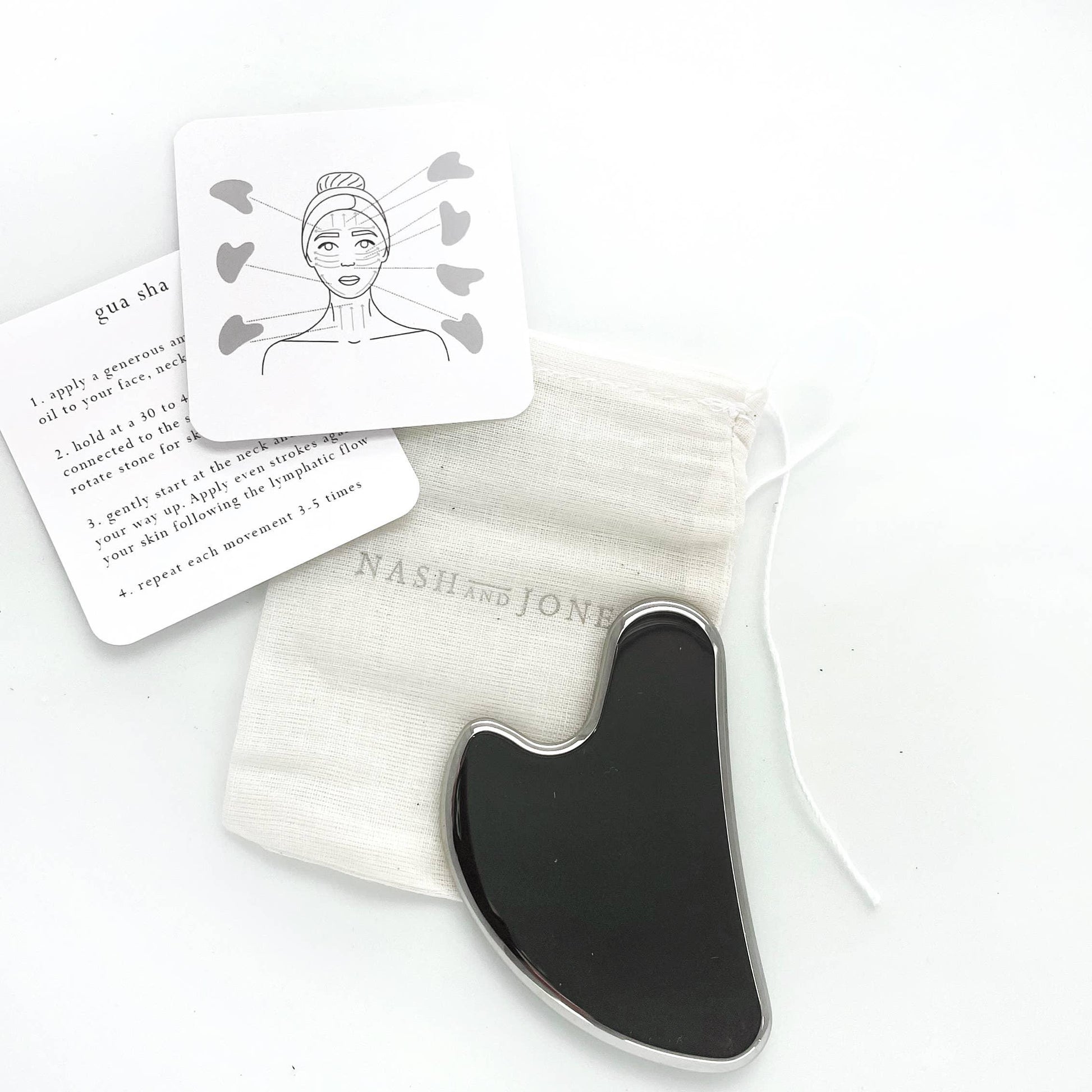Black gua sha tool with instruction cards and pouch on white background. Come see us at Awaken, Franklin, Tennessee