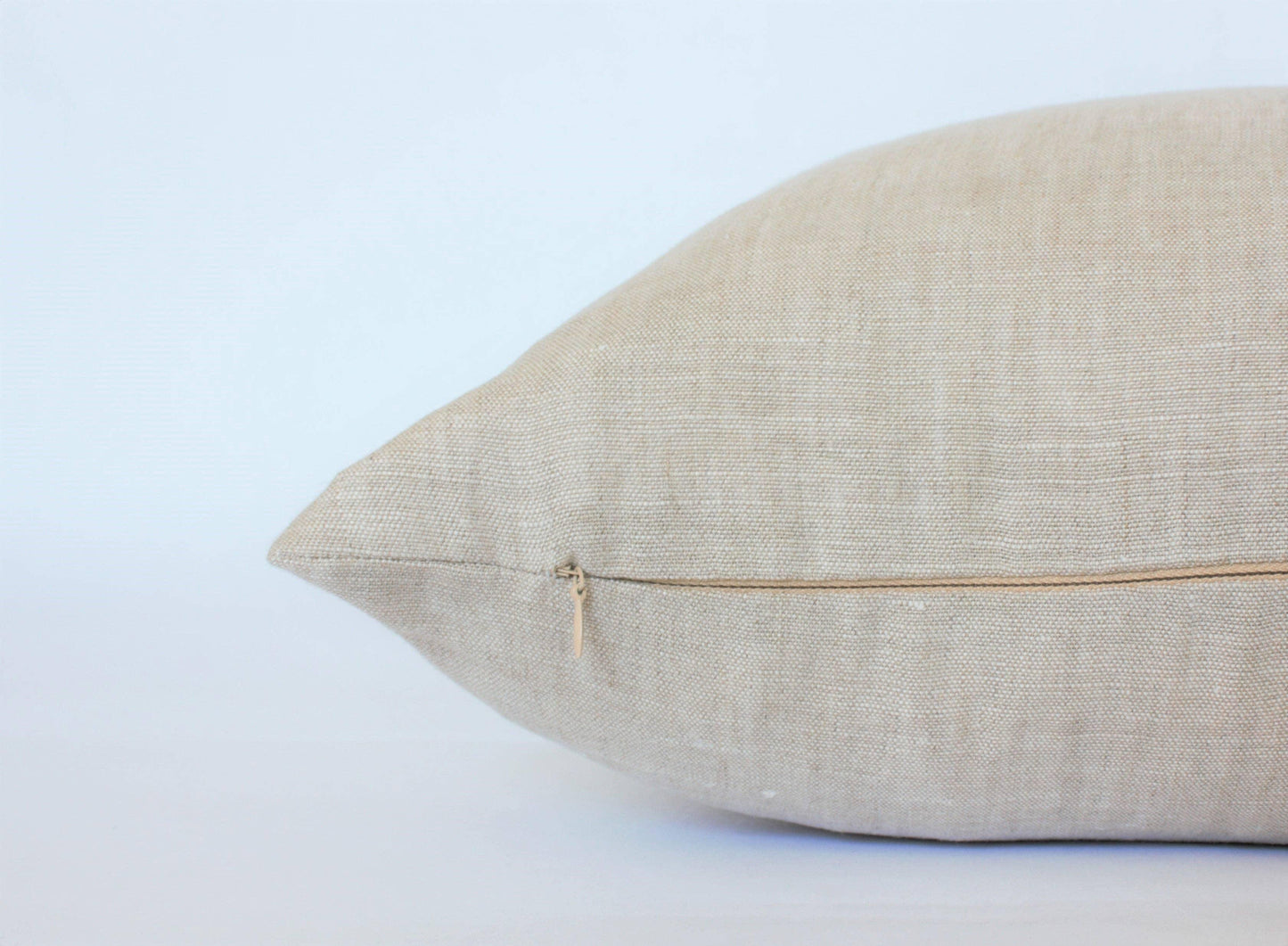 Beige linen pillow with zipper on plain white background. Come see us at Awaken, Franklin, Tennessee