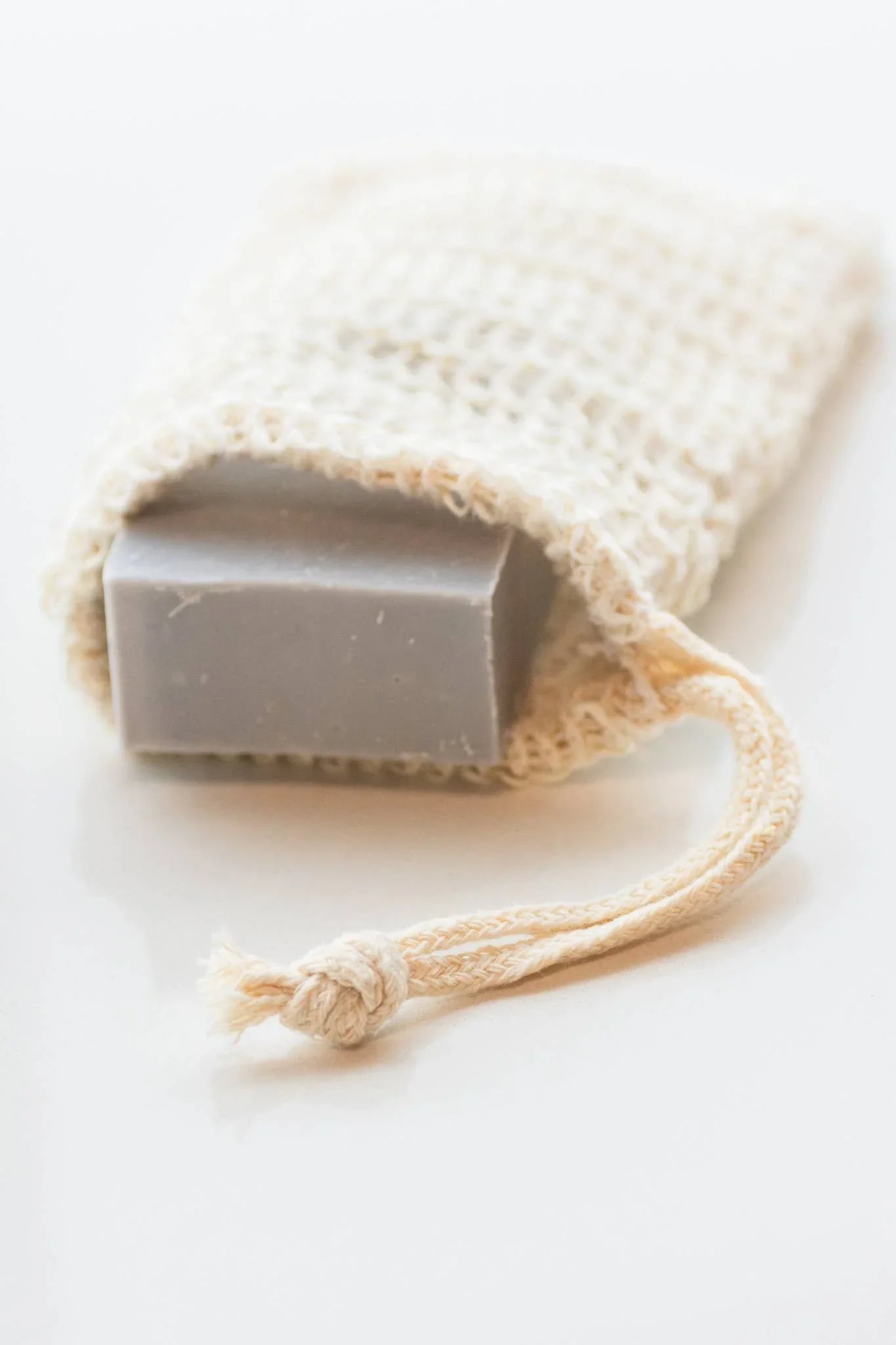 Gray handmade soap bar in a natural textured pouch with drawstring on white surface. Come see us at Awaken, Franklin, Tennessee