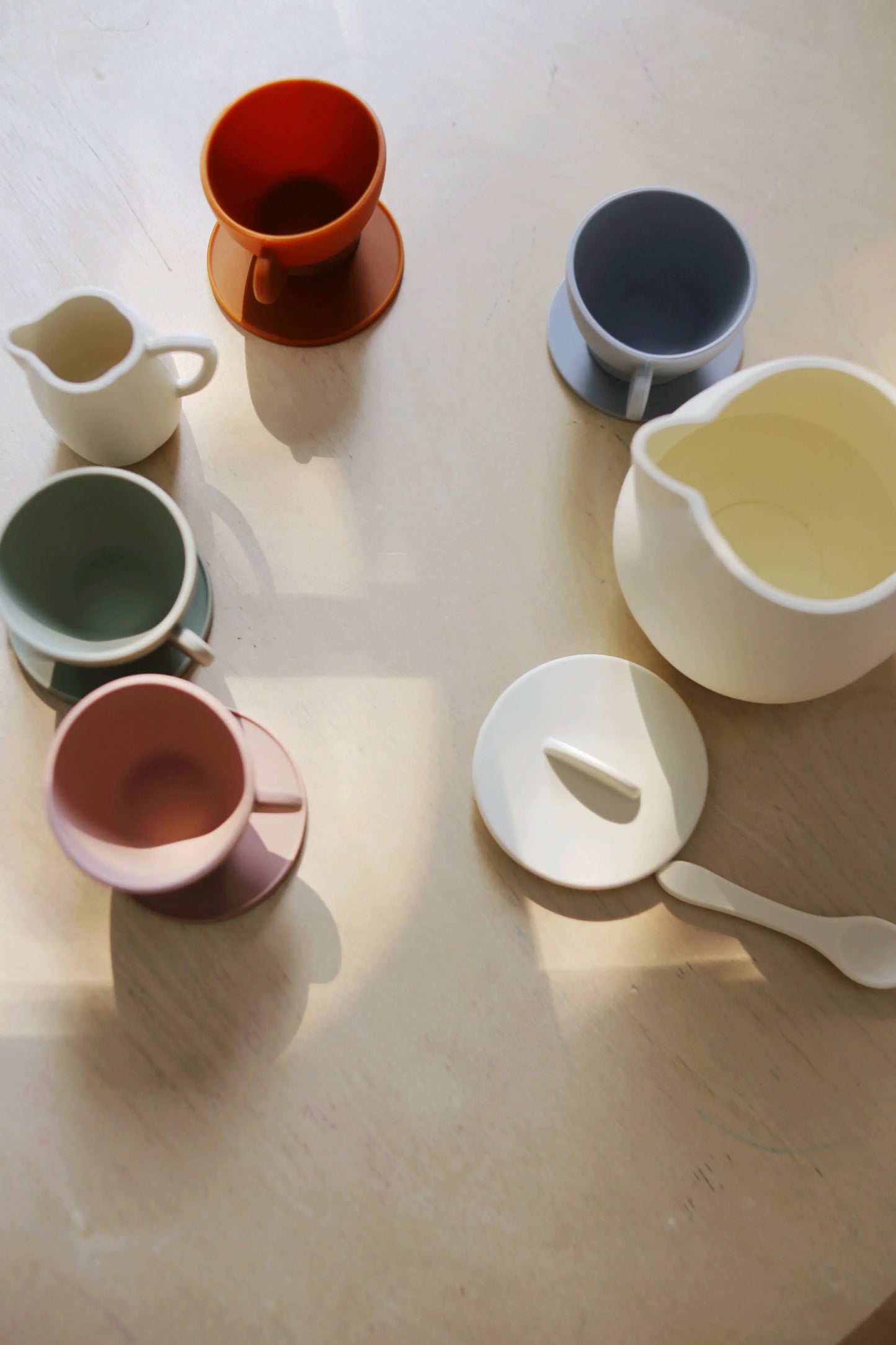 Colorful ceramic cups and pitchers on a wooden table in sunlight. Come see us at Awaken, Franklin, Tennessee.