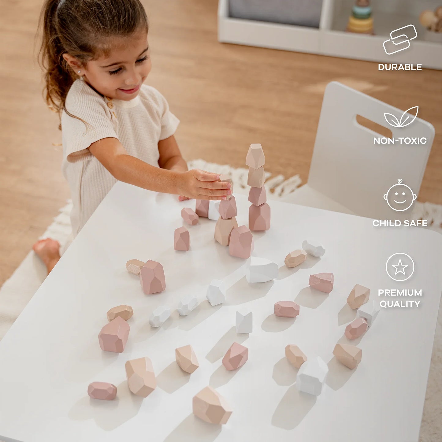 Young girl playing with pastel wooden stacking blocks on white table in bright room. Come see us at Awaken, Franklin, Tennessee